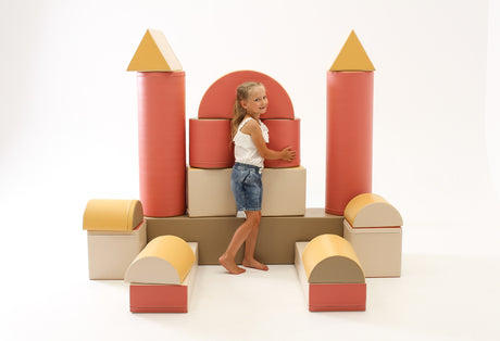 Kind spielt mit bunten, geometrischen Schaumstoffbausteinen in Schlossform