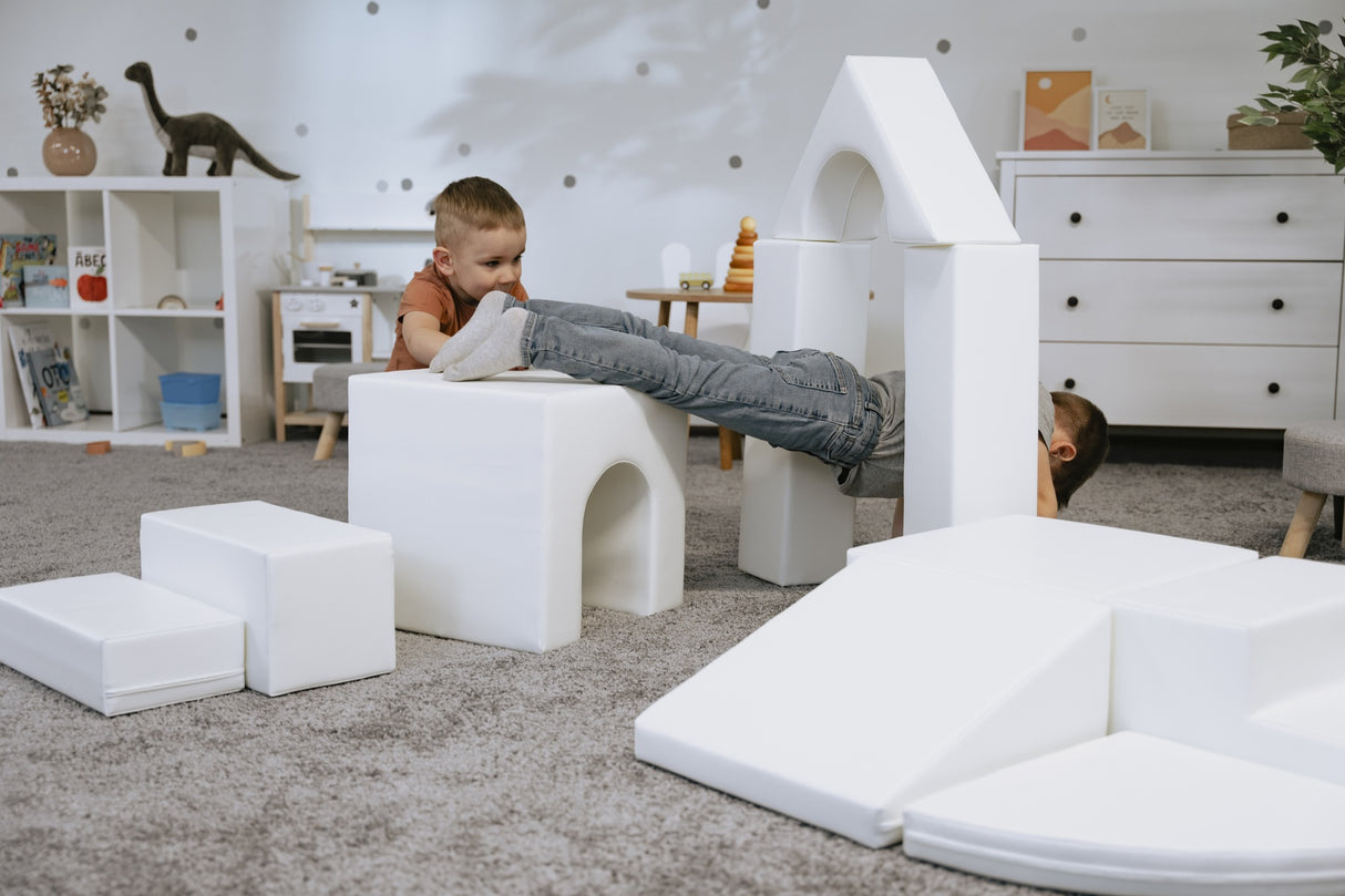 Zwei Kinder spielen mit weißen Bauklötzen in einem Spielzimmer