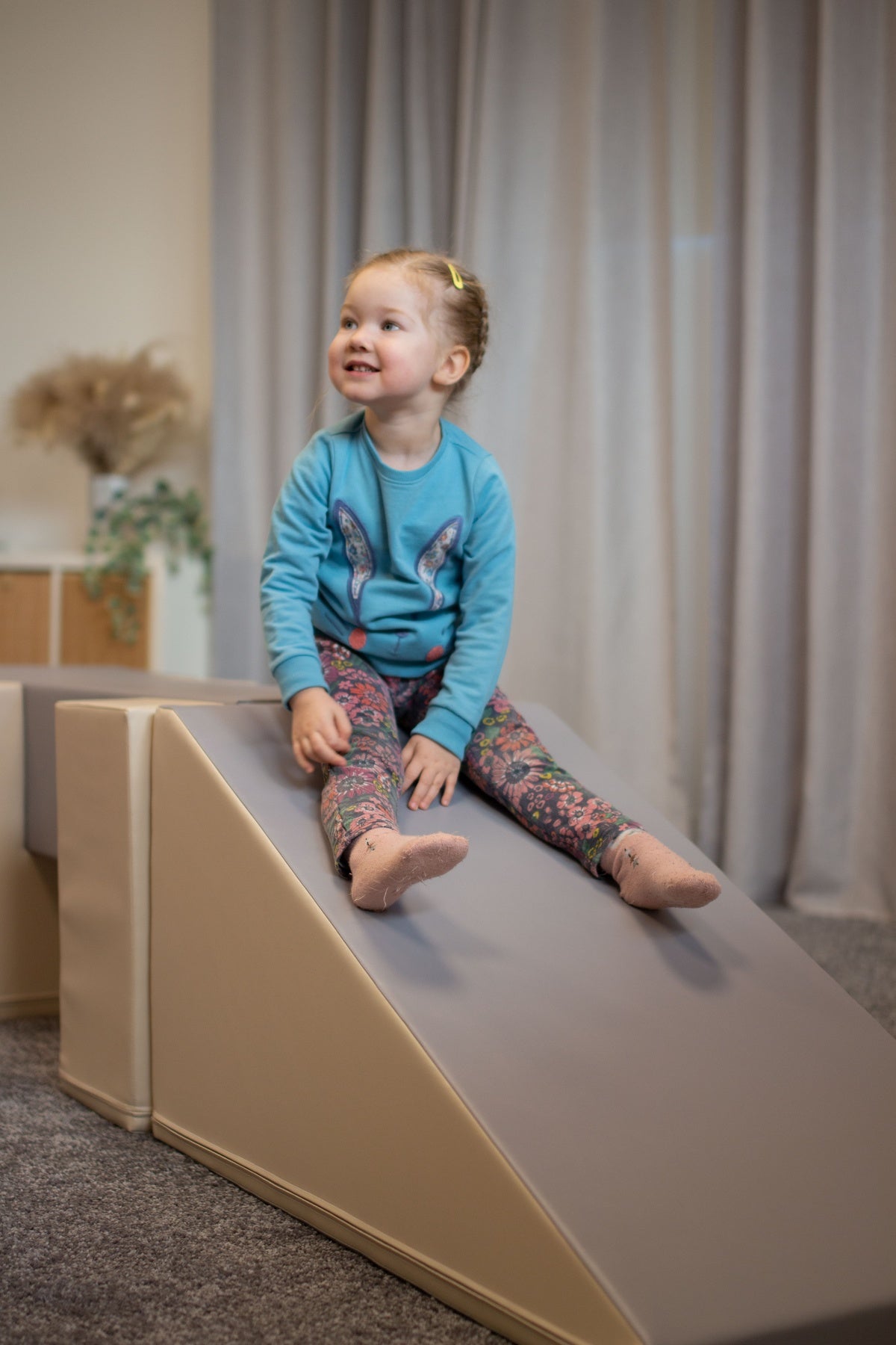 Kleines Kind sitzt auf einer Rutsche aus weichem Material