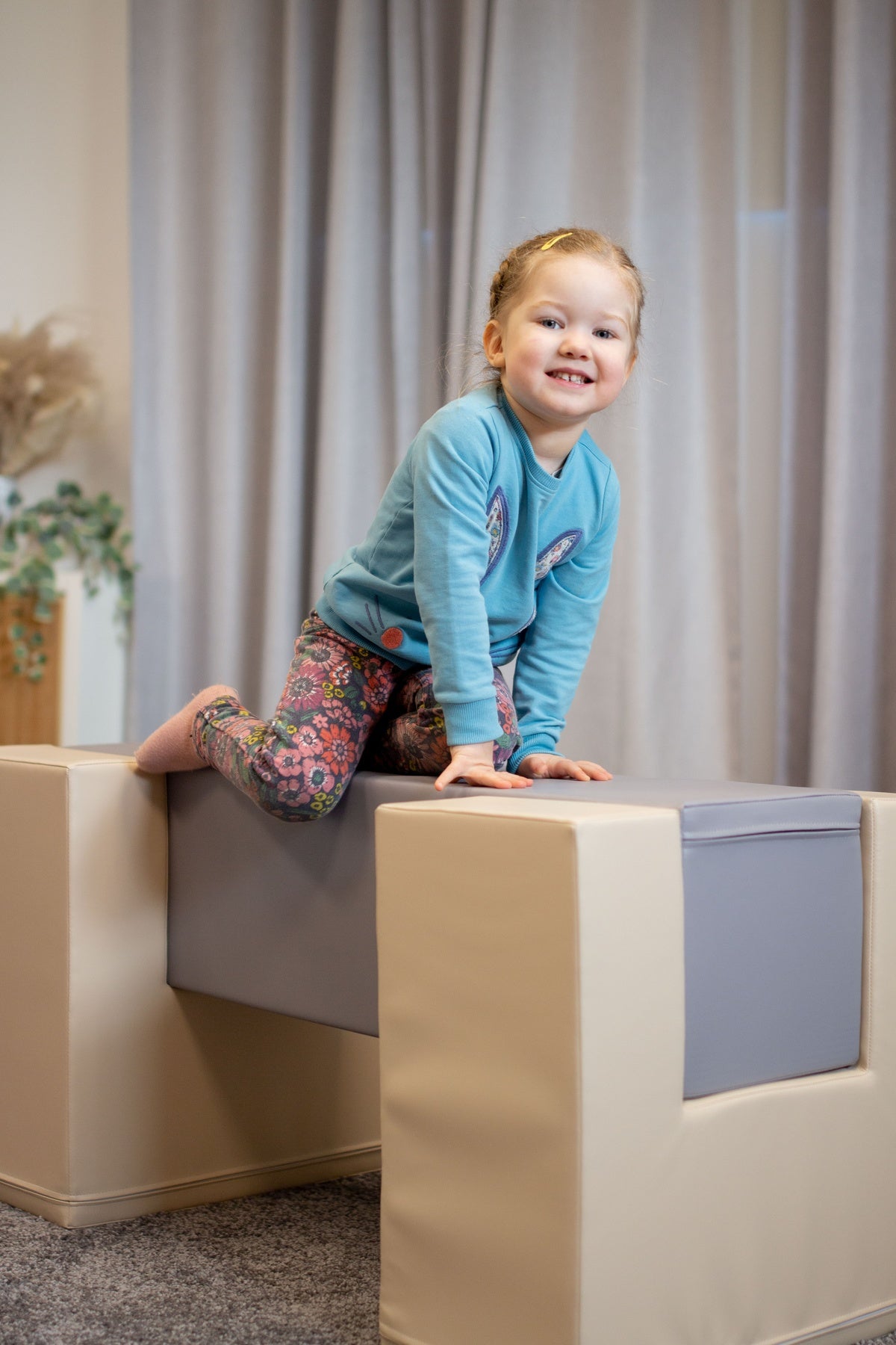 Mädchen spielt auf einem gepolsterten Spielblock in einem hellen Raum