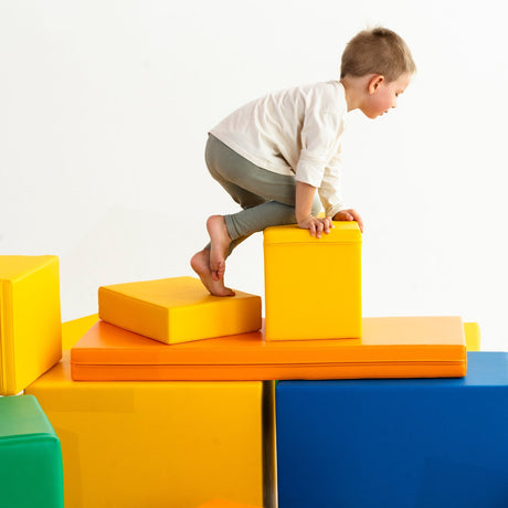 Kind klettert auf bunten, weichen Spielblöcken in verschiedenen Farben