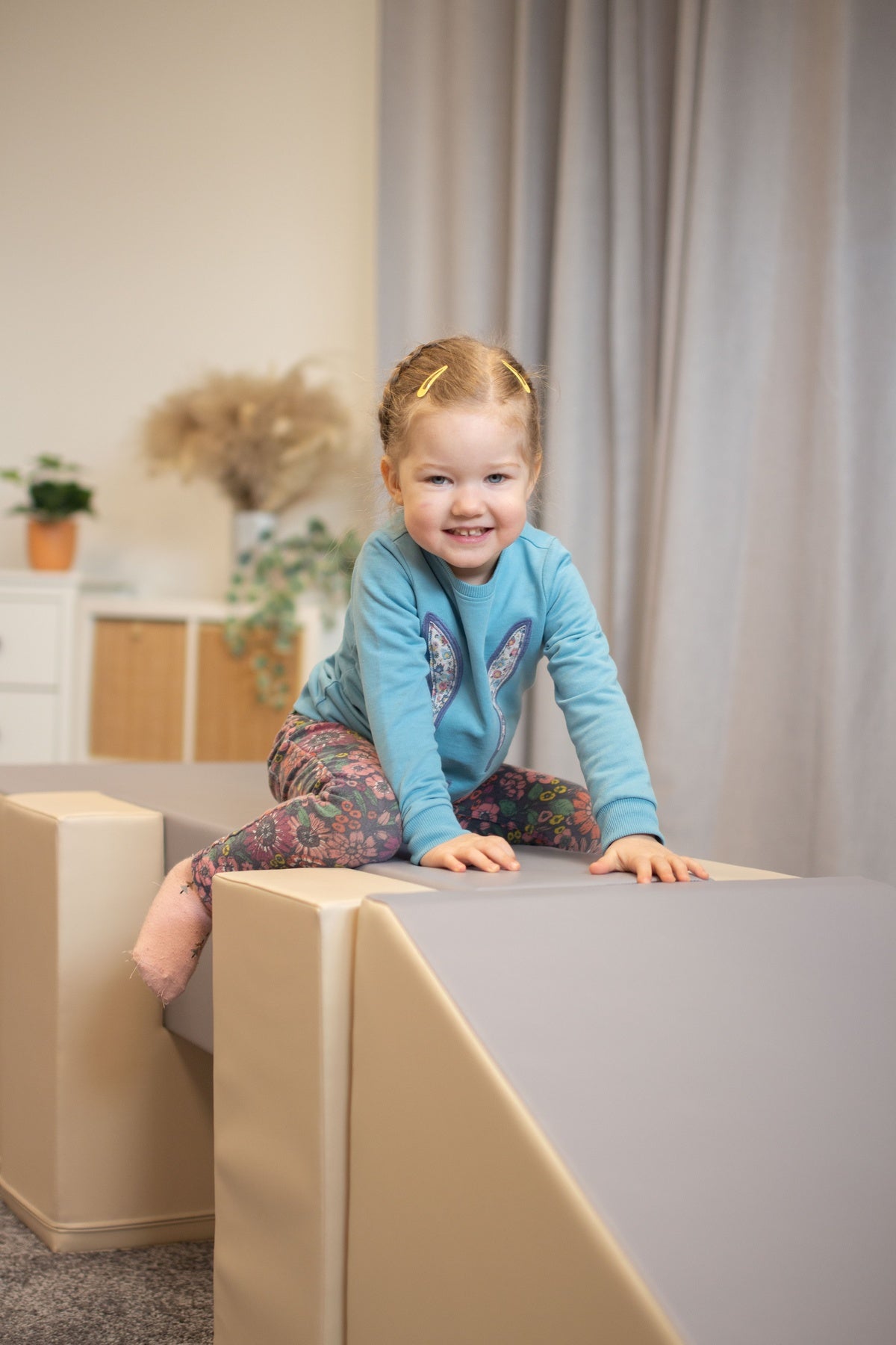 Kleines Mädchen sitzt auf einem Spielblock in einem hellen Raum
