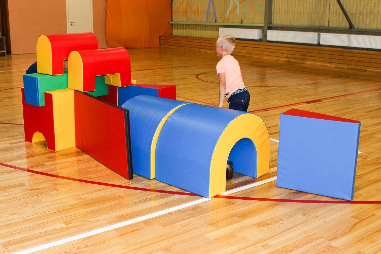 Bunte Schaumstoffbausteine in einer Turnhalle, Kind spielt damit