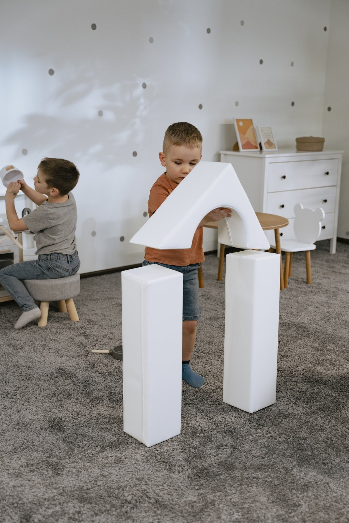 Zwei Kinder spielen mit weißen Schaumstoffbausteinen im Spielzimmer