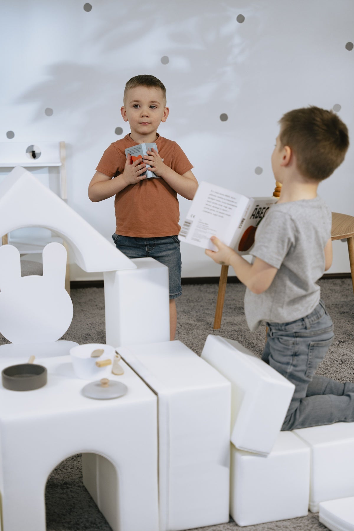 Zwei Kinder spielen mit Schaumstoffbausteinen und lesen ein Buch