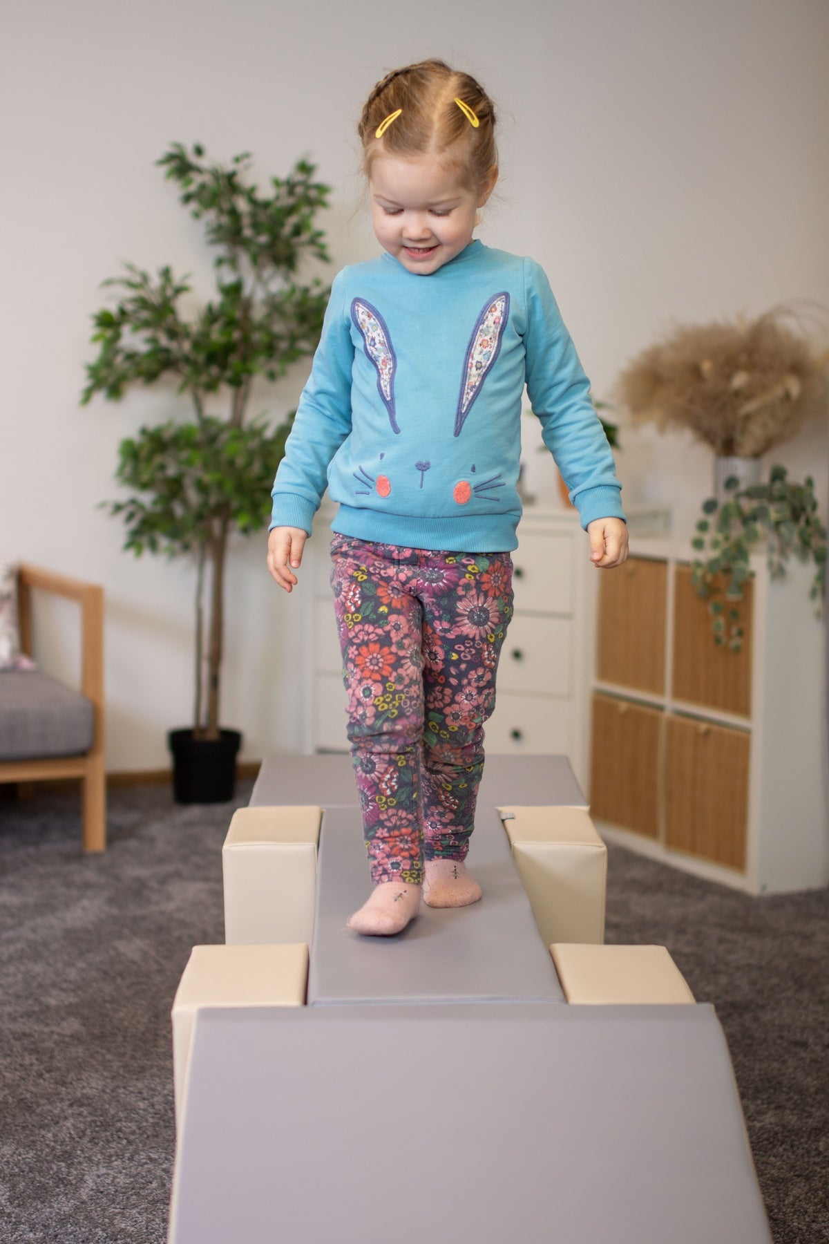 Kleines Mädchen balanciert auf einer Spielbrücke in einem hellen Raum