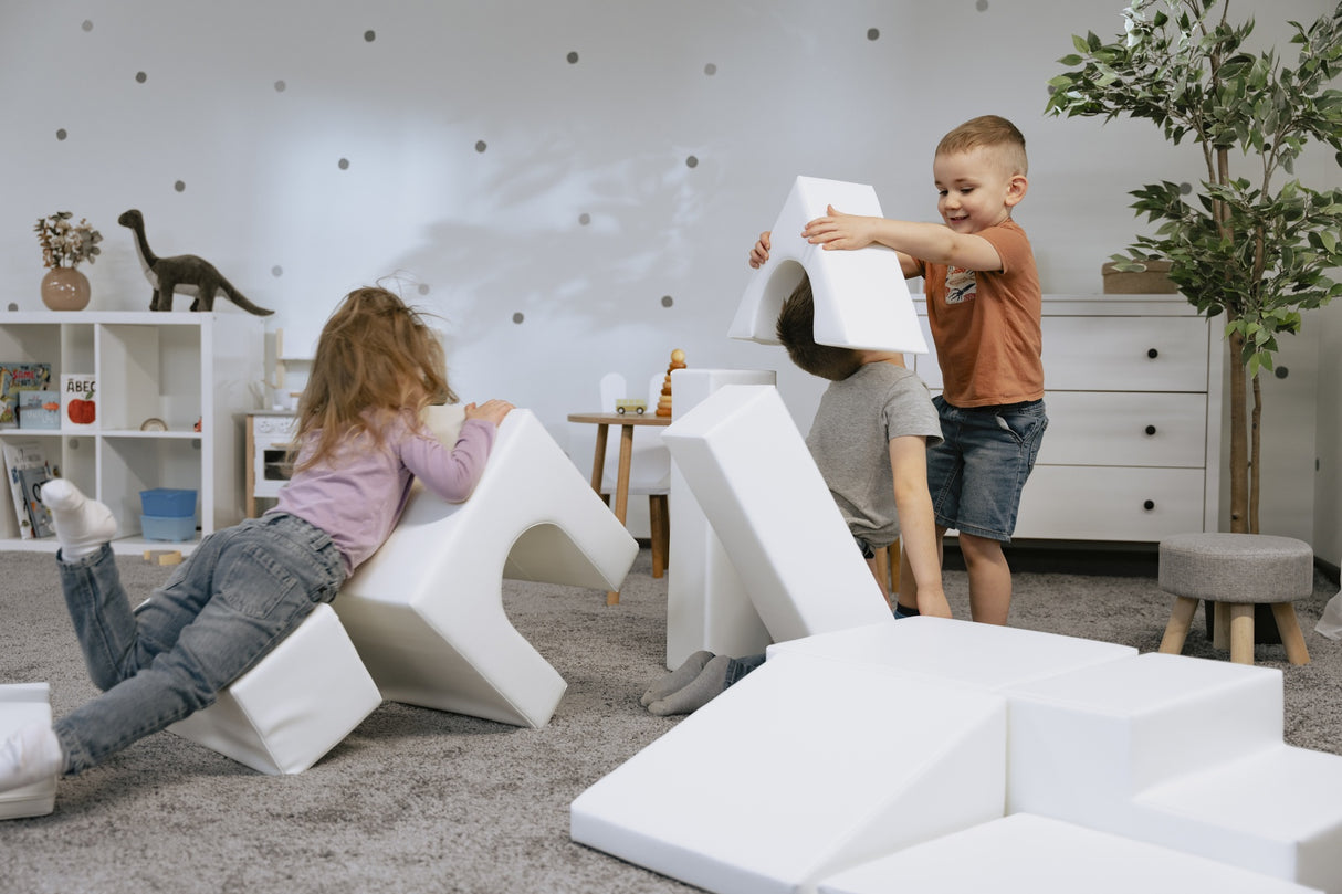 Kinder spielen mit weißen Schaumstoffbausteinen im Spielzimmer