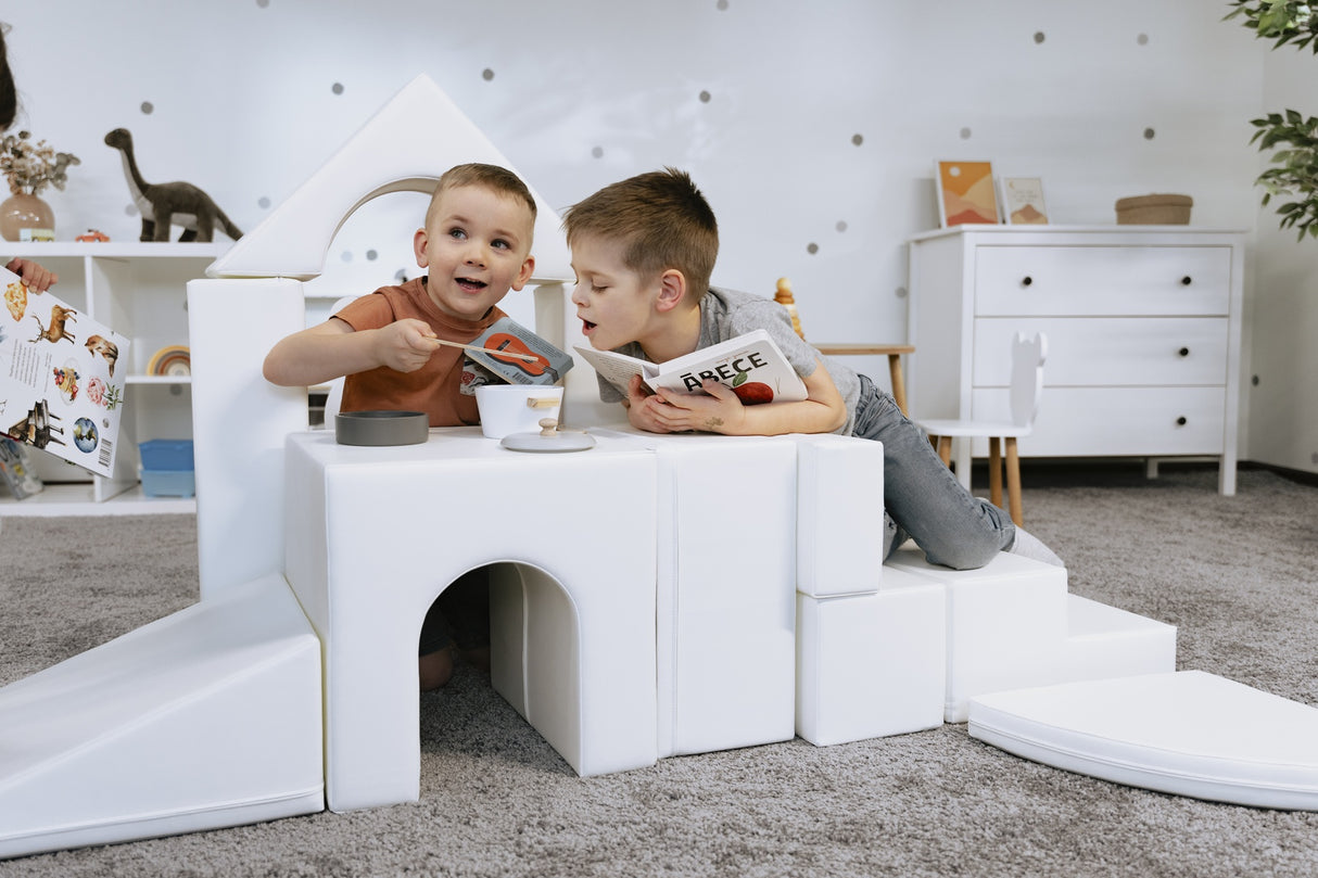 Zwei Kinder spielen mit Bausteinen in einem hellen Raum