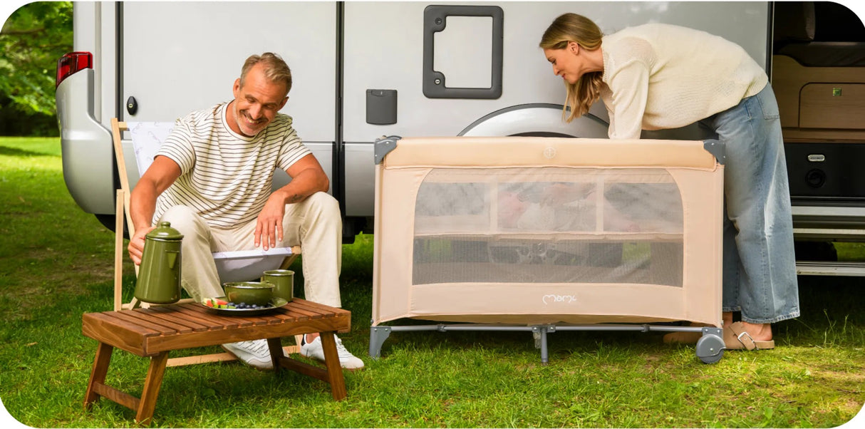 Paar entspannt im Freien mit einem tragbaren Babybett und Campingausrüstung