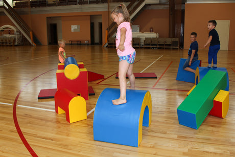 Kinder spielen auf bunten Bewegungsbausteinen in einer Sporthalle