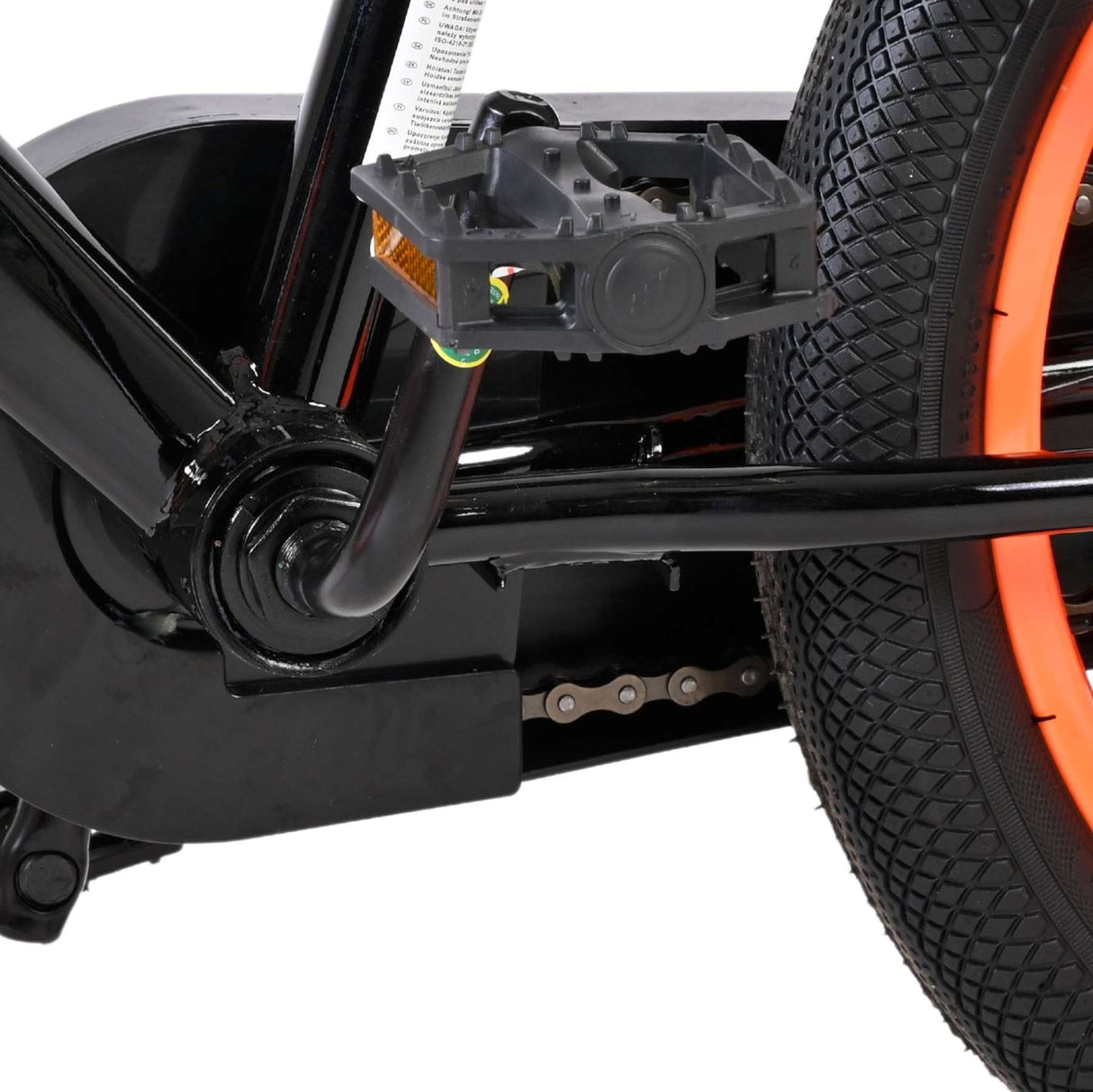 Schwarzes Fahrradpedal mit orangefarbenem Reifen und Kette im Hintergrund