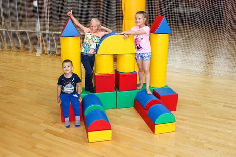 Drei Kinder spielen mit bunten Schaumstoffbausteinen in einer Sporthalle