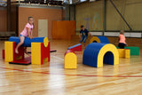 Kinder spielen auf bunten, geometrischen Spielmodulen in einer Sporthalle