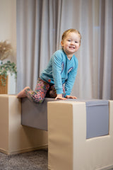 Mädchen spielt auf einem gepolsterten Spielblock in einem hellen Raum