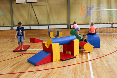 Kinder spielen mit bunten Schaumstoffbausteinen in einer Sporthalle