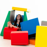 Kind sitzt entspannt zwischen bunten Schaumstoffbausteinen in verschiedenen Formen