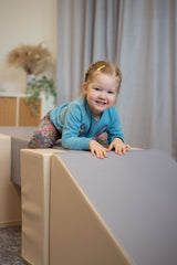 Kind klettert fröhlich auf einer weichen Spielstruktur in einem Raum