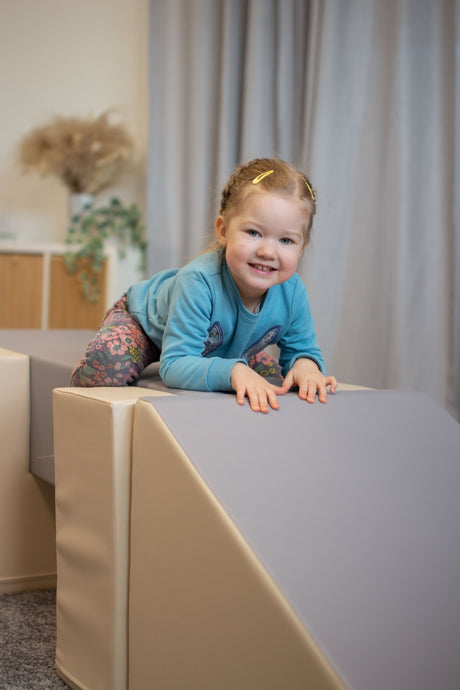 Kind klettert fröhlich auf einer weichen Spielstruktur in einem Raum