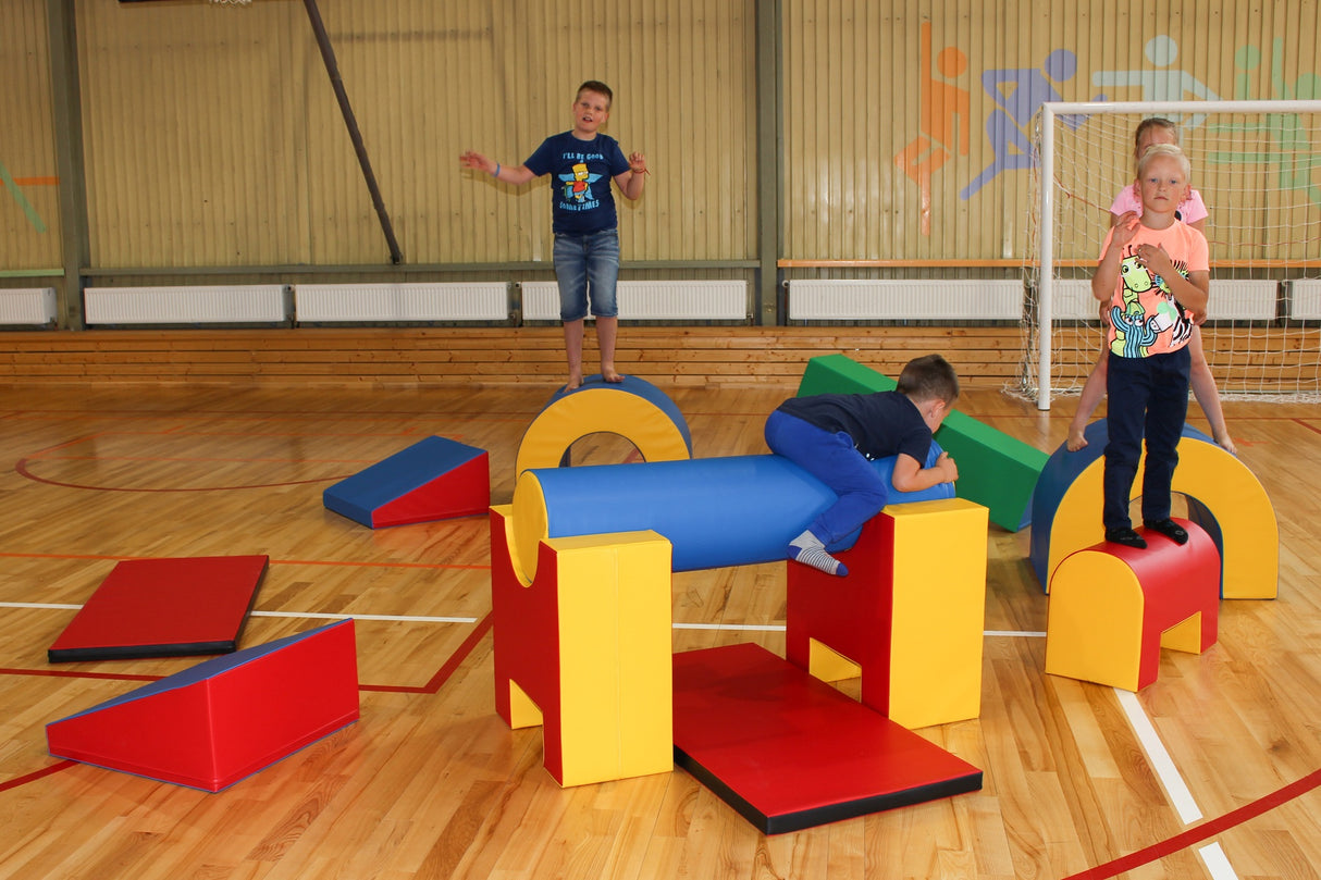 Kinder spielen auf bunten Kletterelementen in einer Sporthalle