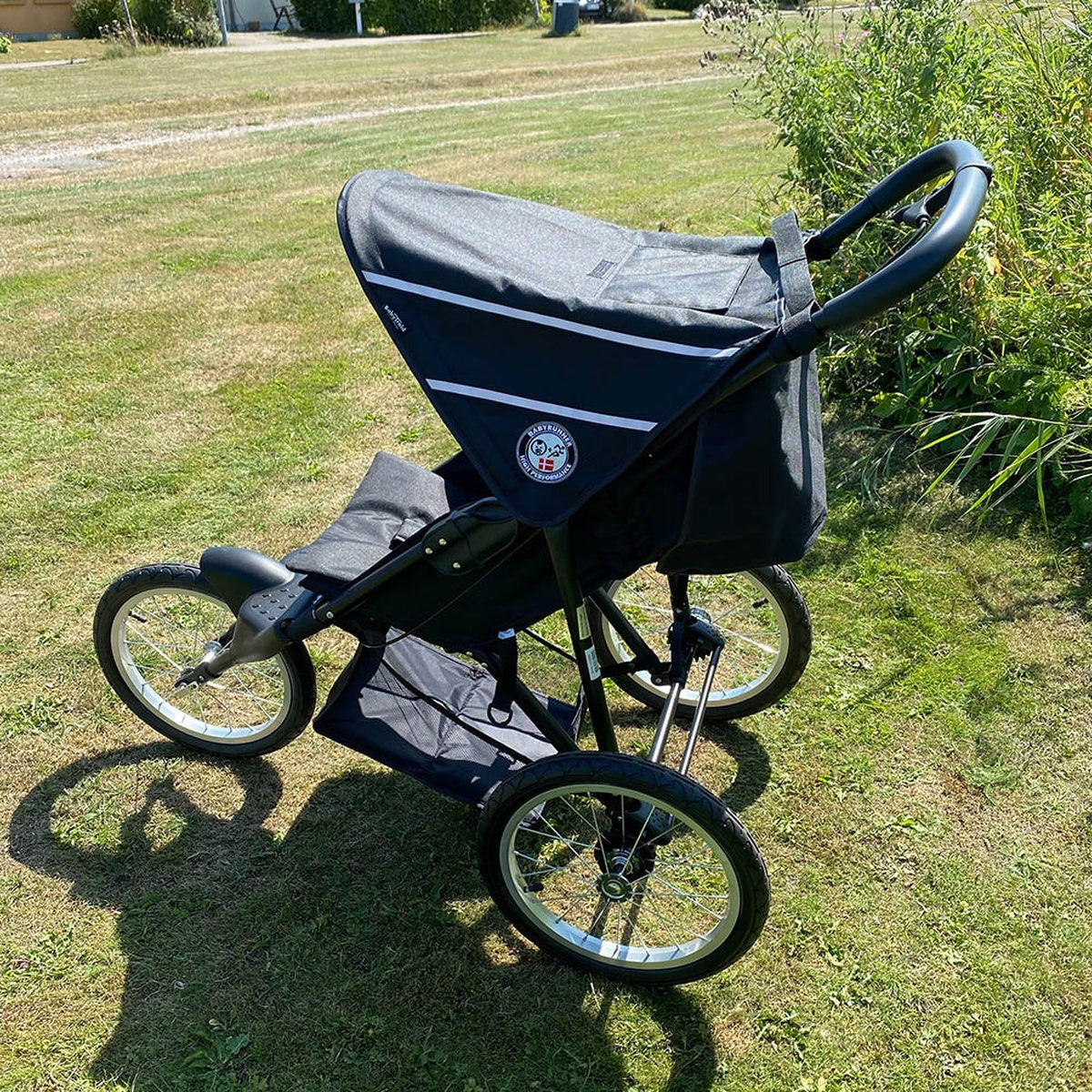 Baby trold Jogger schwarz Seitenansicht von oben auf der Wiese geschlossenen Sonnenschutz