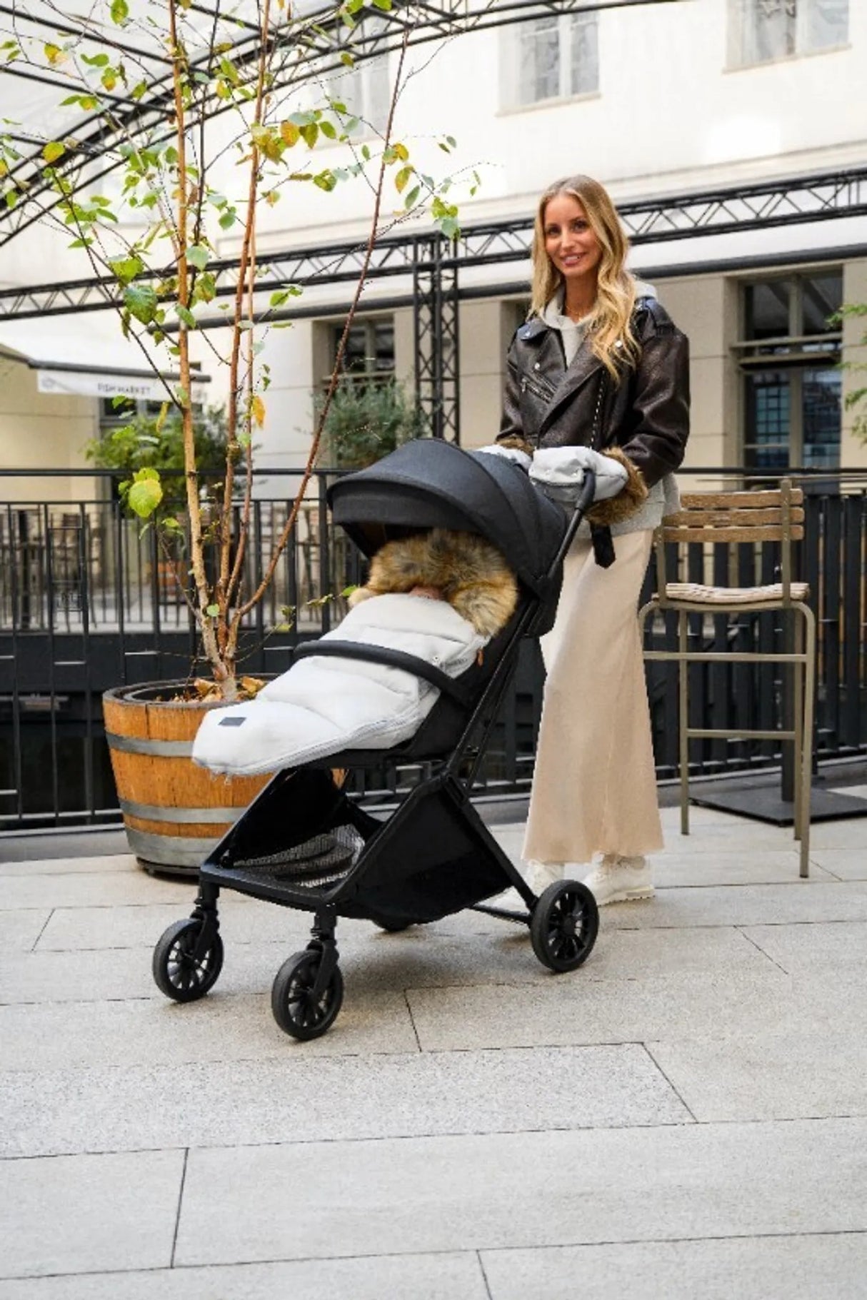 Frau mit Kinderwagen in urbaner Umgebung, stilvolles Design und warme Decke