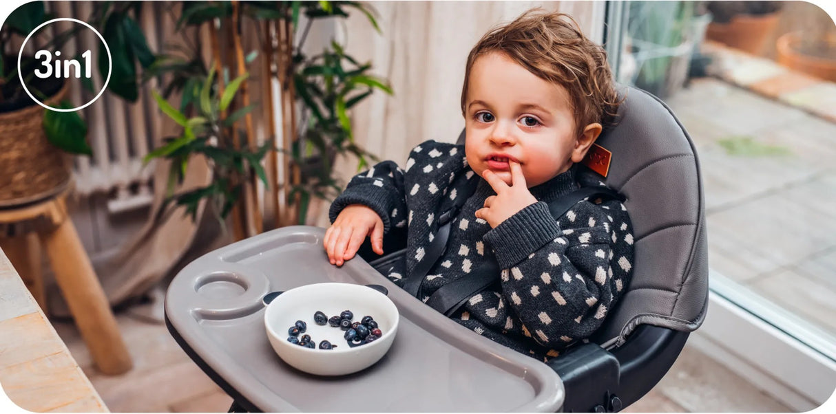 Hochstuhl mit Kind, das Beeren aus einer Schüssel isst
