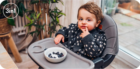 Hochstuhl mit Kind, das Beeren aus einer Schüssel isst
