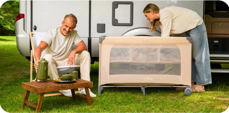 Paar entspannt im Freien mit einem tragbaren Babybett und Campingausrüstung