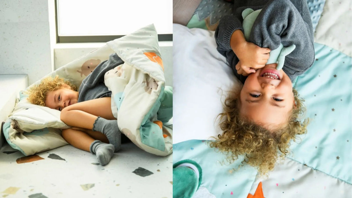Kind schläft eingekuschelt in einer bunten Decke auf dem Boden
