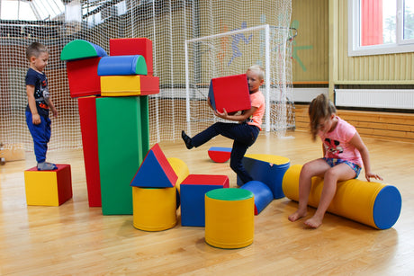 Kinder spielen mit bunten, geometrischen Bauklötzen in einem Raum