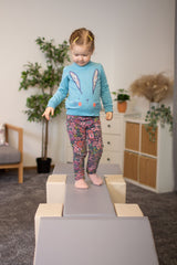 Mädchen balanciert auf einem Spielgerät in einem hellen Raum