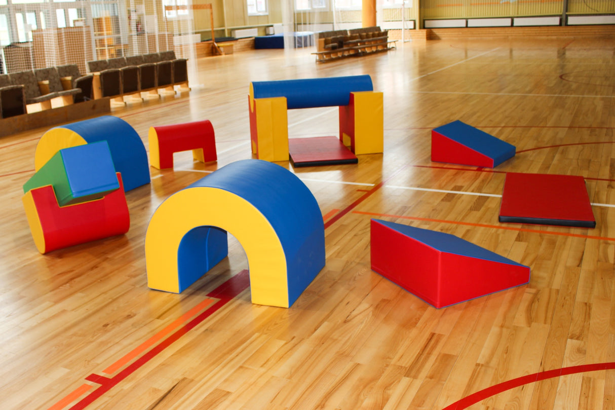 Bunte Schaumstoffspielgeräte in verschiedenen Formen auf einem Holzboden