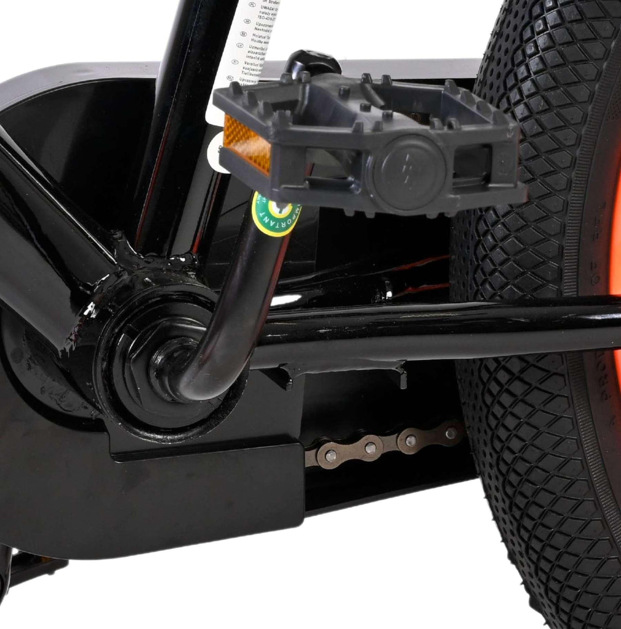 Schwarzes Fahrradpedal mit reflektierendem Element und Kette sichtbar