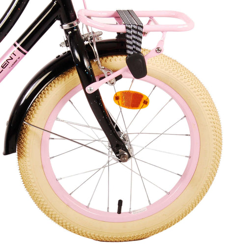 Schwarzes Fahrrad mit pinkem Gepäckträger und breitem, beigem Reifen