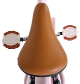 Brauner Fahrradsattel mit runden, braunen Pedalen in rosa Rahmen