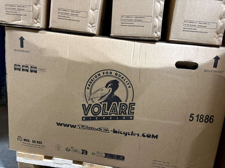 Karton mit Fahrradverpackung und Logo in Schwarz auf braunem Hintergrund
