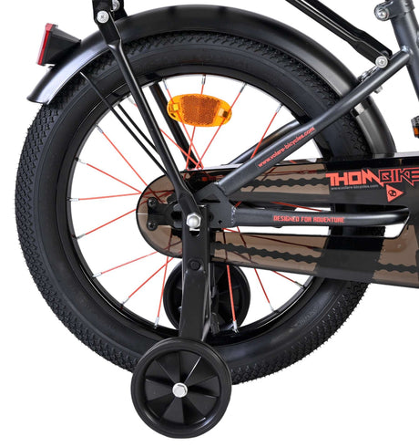 Hinterrad eines Fahrrads mit Stützrädern und orangefarbenem Reflektor
