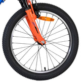 Vorderreifen eines Fahrrads mit orangefarbener Gabel und Reflektor