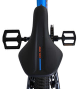 Schwarzer Fahrradsattel mit blauen Akzenten und Pedalen im Hintergrund