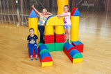 Drei Kinder spielen mit bunten Schaumstoffbausteinen in einer Sporthalle