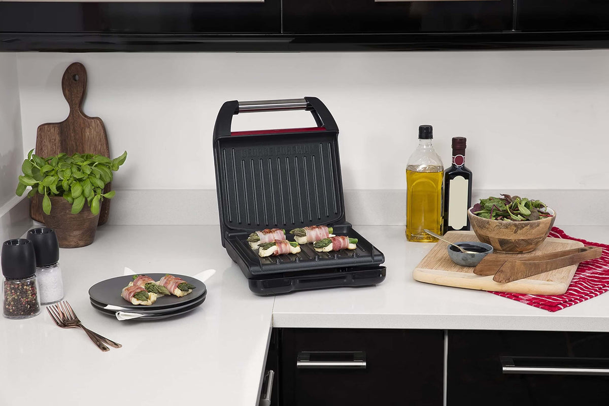 George Foreman Kontaktgrill in der Küche mit geöffnetem Deckel und Küchenutensilien